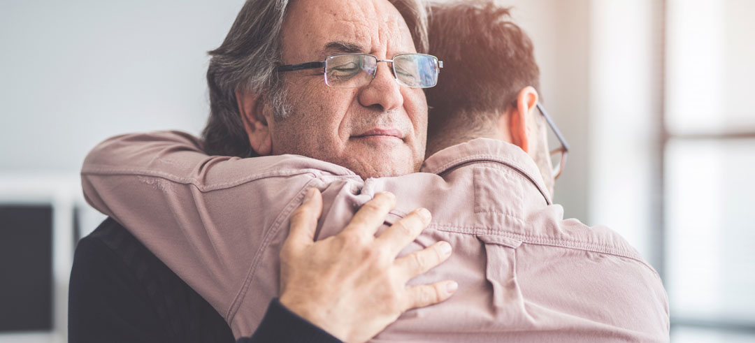 Dos hombres abrazándose con los ojos cerrados