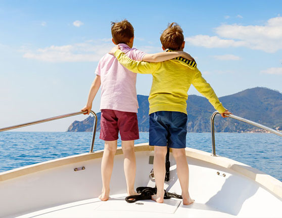 Dos niños agarrados en la proa de un barco mientras navega