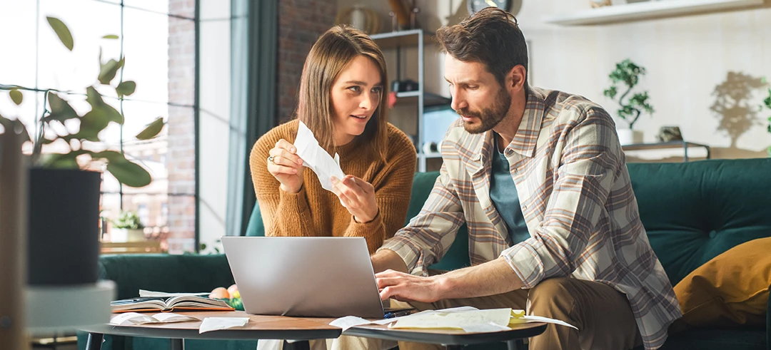 Pareja revisando documentos y escribiéndolo en el ordenador