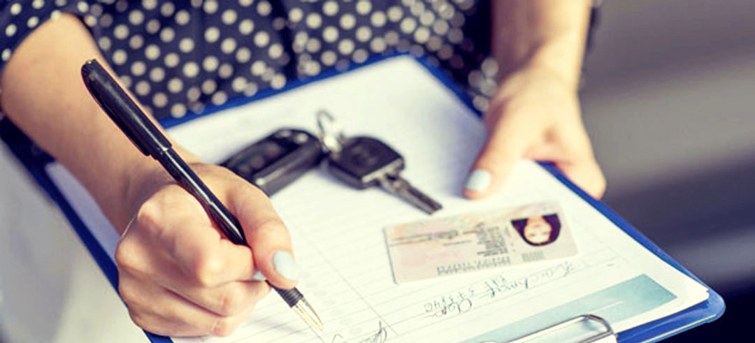 Persona rellenando documentación con carnet de conducir y llaves de coche