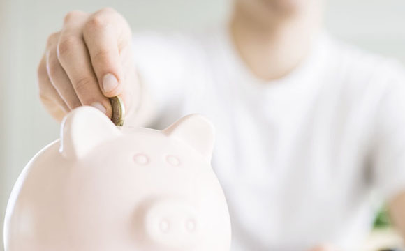 Persona introduciendo una moneda en una hucha